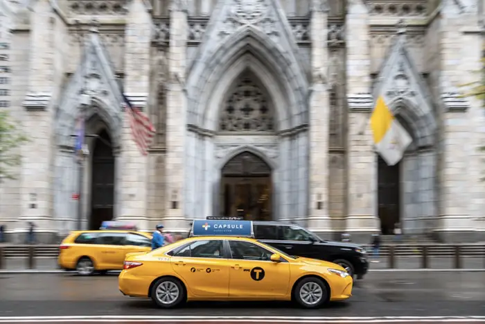 a yellow cab drives past St. Patrick's Cathedral
